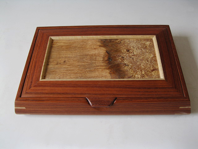 This wooden jewelry box has a lid that lifts to reveal trays with various dividers